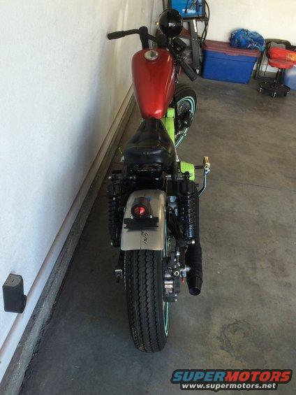 Rear view of a custom motorcycle with a red fuel tank and green frame