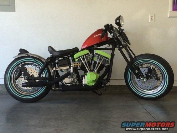 Custom motorcycle with red tank, green engine covers, and whitewall tires