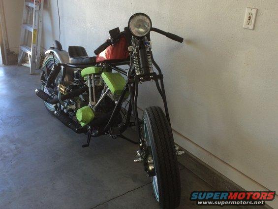 Front view of a custom motorcycle with green engine covers and a red gas tank