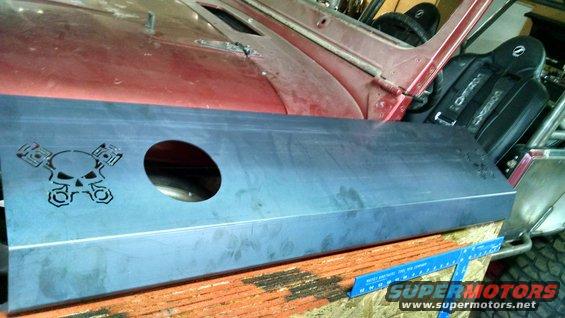 Custom metal door panel with skull and crossed pistons graphic, next to a red vehicle interior