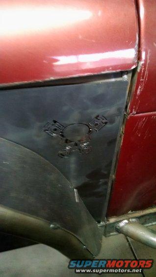 Red vehicle fender with a custom black metal panel a skull and piston cutouts