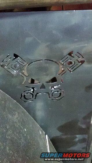 Skull and piston emblem on dark metal surface