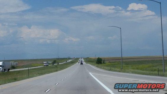 Highway with multiple vehicles and streetlights under a cloudy sky
