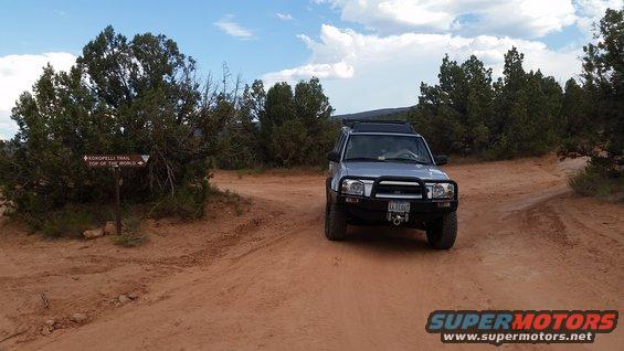 Silver SUV parked on a dirt road near a trail sign