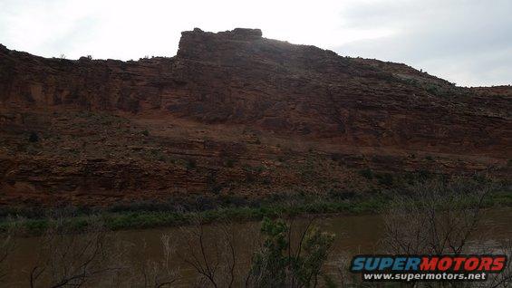 Rocky cliff face above a river, with "SUPERMOTORS" watermark
