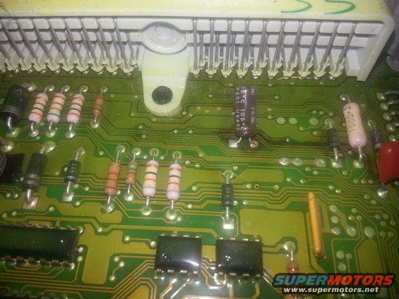 Close-up of a green circuit board with various electronic components and a white connector