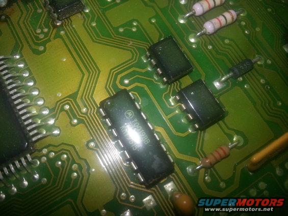 Close-up of a green circuit board with multiple integrated circuits, resistors, and diodes