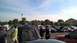 2004 Ford Crown Victoria - People mill around a parking lot filled with cars, some with their hoods open, under a partly cloudy sky.