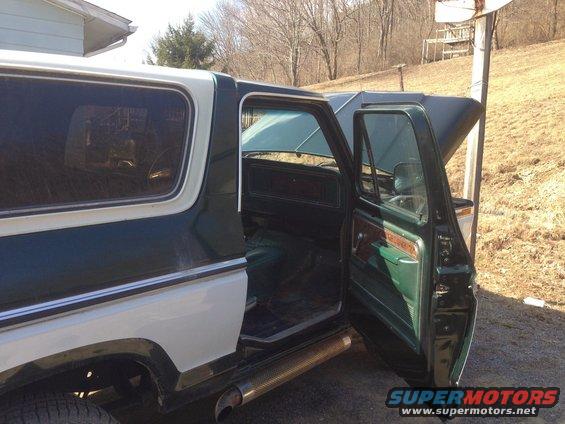 Interior of a 1979 Ford Bronco with green and wood trim, doors open