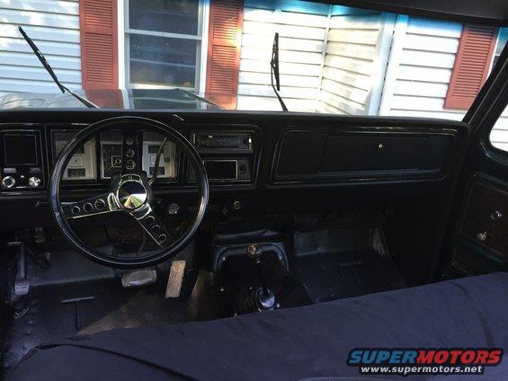 1979 Ford Bronco interior with black dashboard, steering wheel, and floor mats