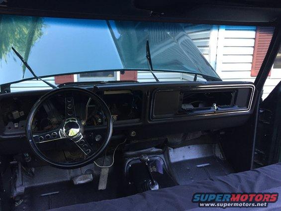 1979 Ford Bronco interior dashboard with aftermarket steering wheel and removed radio
