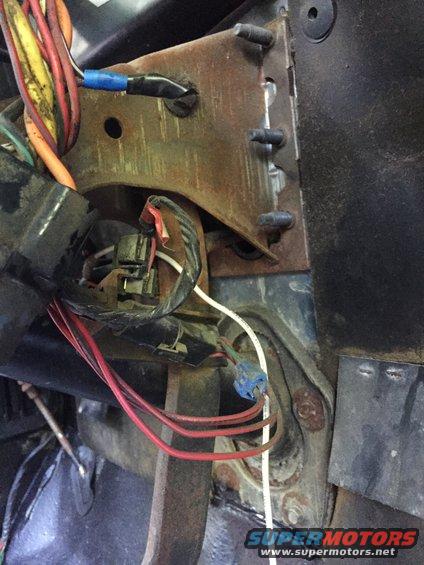 Wiring harness connected to a rusty bracket under the dashboard
