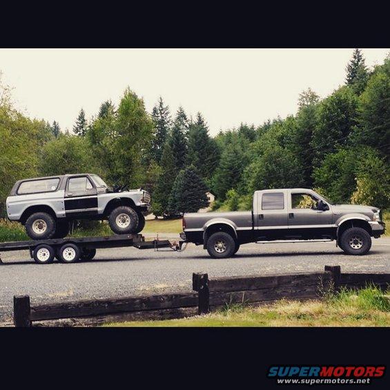Gray 1978 Ford Bronco on a trailer towed by a gray and black Ford F-Series truck, side view