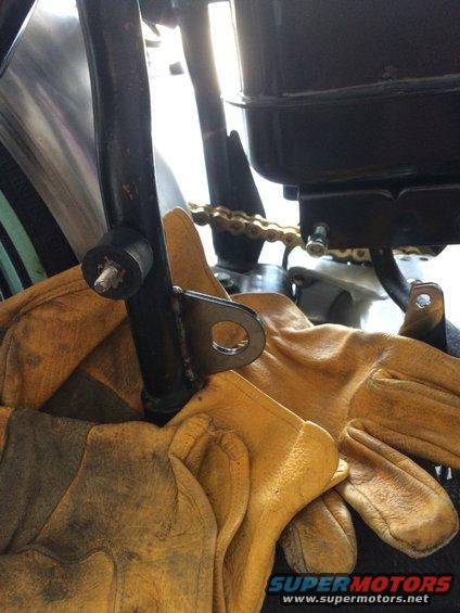 Motorcycle frame bracket with a gold chain and yellow work gloves