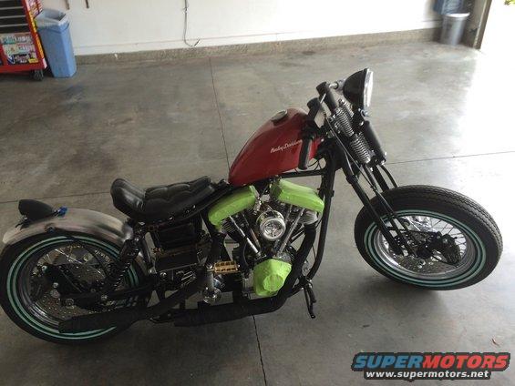 Red Harley-Davidson motorcycle with green engine covers and a silver rear fender. The motorcycle is on a concrete floor