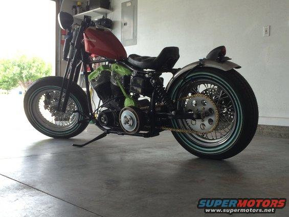 Custom motorcycle with red gas tank and green engine in a garage