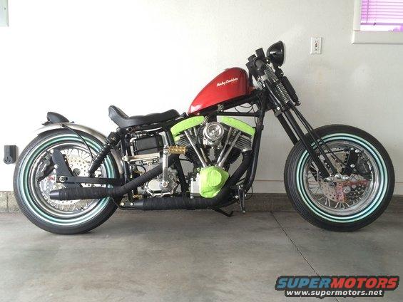 Red fuel tank Harley-Davidson motorcycle with black frame and exhaust, green engine covers, and whitewall tires