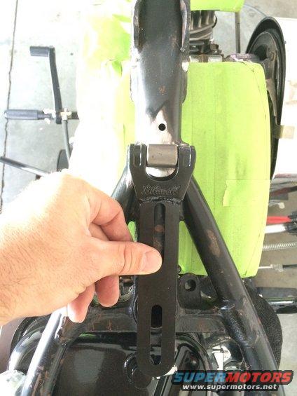Hand holding black metal bracket with 'Klock Werks' visible on motorcycle frame