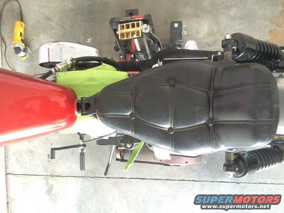Black tufted motorcycle seat and red fuel tank with a chrome air cleaner housing
