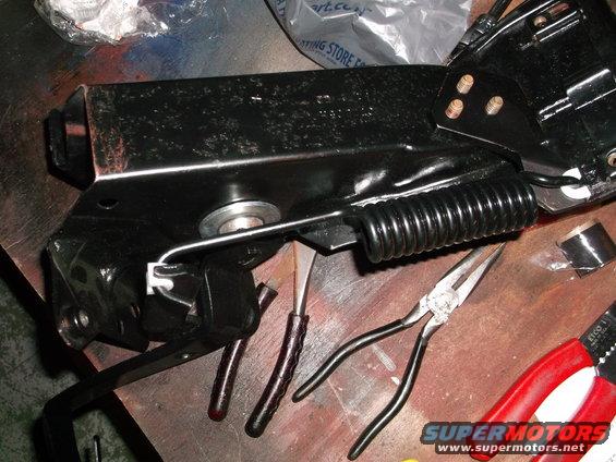 Black metal automotive part with coiled spring and pliers