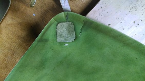 Green headliner with a square patch of exposed material and torn edges