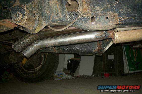 Underside view of a vehicle's exhaust system with a new pipe welded to the muffler