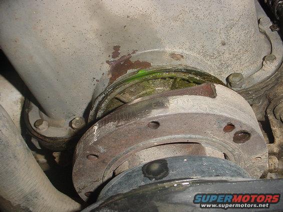 Close-up of a leaking water pump assembly with green coolant visible