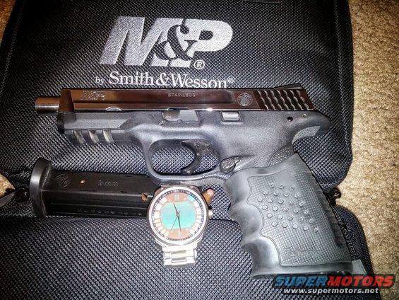 Smith & Wesson M&P pistol, loaded magazine, and a wristwatch laid out on a black Smith & Wesson branded bag