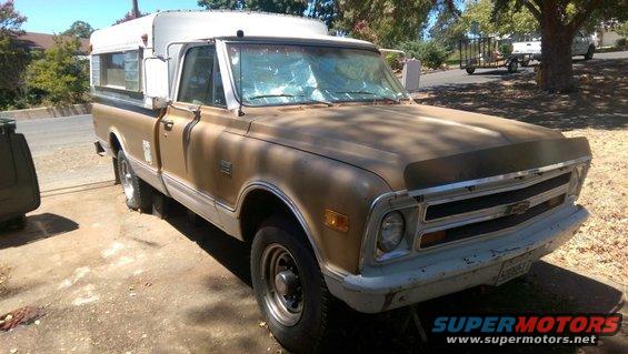 Brown pickup truck with a camper shell, front end visible. Grille has horizontal bars and a Chevrolet emblem