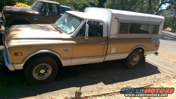1969 Chevrolet C/K Pickup with a white camper shell parked next to a brown Ford pickup truck