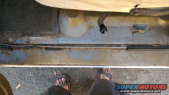 Interior floor and door sill of a vehicle, showing a black shift knob and part of the seat