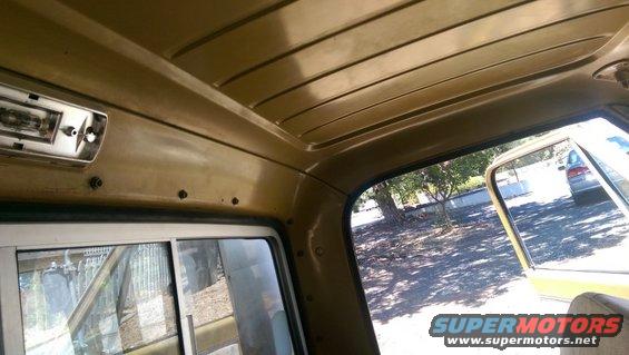Interior view of a truck cab looking out the passenger window at another vehicle parked outside