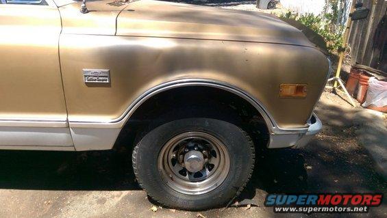 Gold and white pickup truck fender and wheel. Badge reads 'Custom Camper'