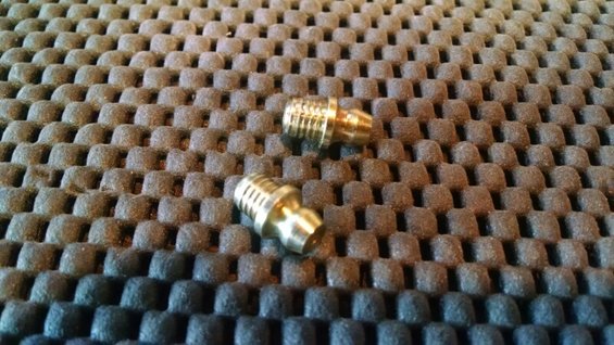 Two brass fittings on a textured surface