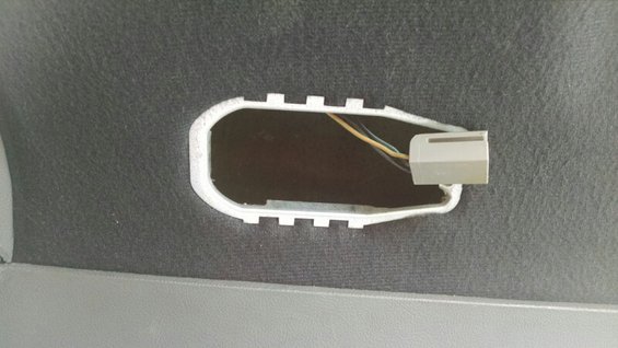 Interior trim panel with an open oval cutout revealing wires and a gray connector