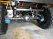 1992 Ford Bronco - Close-up view of the rear axle, suspension, and large tires of a vehicle, with visible blue brake calipers.