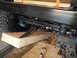 1992 Ford Bronco - The underside of a vehicle is shown with wooden supports and visible mechanical components.