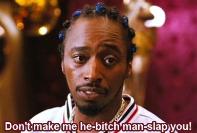 Man with braids and a gold chain, wearing a white jacket with red and blue stripes. Text overlay reads 'Don't make me he-bitch man-slap you!'