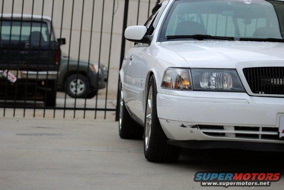 White sedan parked next to a black truck behind a fence