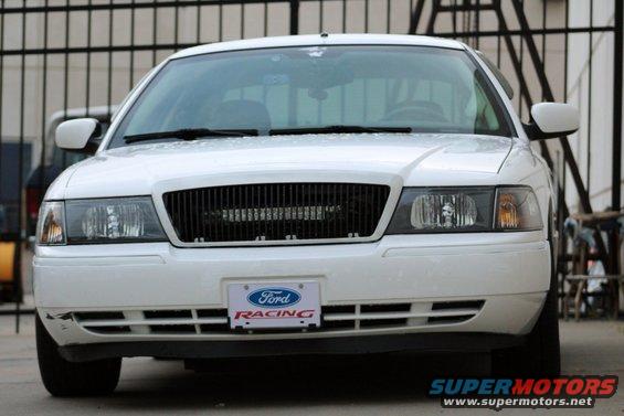 White sedan front view, black grille, Ford Racing license plate frame