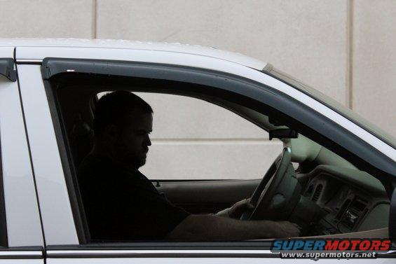 White sedan interior with driver, side view. Dashboard and steering wheel visible