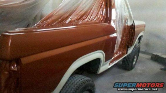 1982 Ford Bronco with doors open, covered in plastic, being painted brown and white