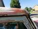 1970 Ford F-250 - This photo shows significant rust damage on the cab corner of a truck, with a reflection of a person in the window.