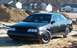 1990 Ford Taurus - This black sedan, likely a 1986 model, is shown in a construction area with houses behind it.
