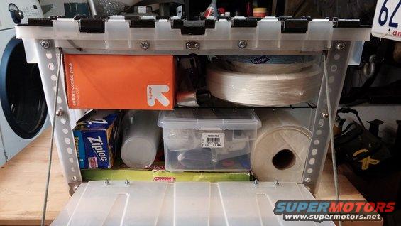 Open storage box with cutlery, Ziploc bags, tape, and paper towels inside