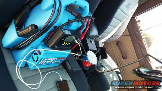 Interior view of a vehicle with a blue power inverter and charging equipment connected to a phone