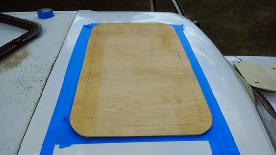 Sunroof opening with plywood template and blue tape on vehicle roof