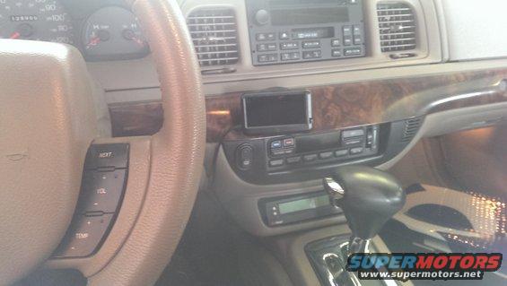 Interior shot of a 2000 Mercury Grand Marquis showing the steering wheel, dashboard, and center console with a GPS device mounted
