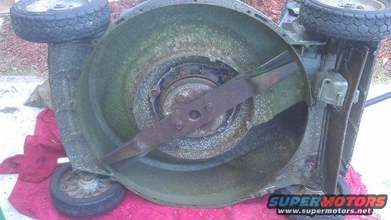 Underside of a lawn mower deck showing the blade and wheels