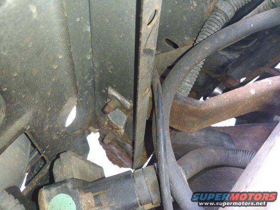 rusted metal bracket with wiring harness and hoses attached